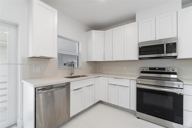 kitchen with white cabinetry, stainless steel appliances, tasteful backsplash, sink, and light tile patterned flooring