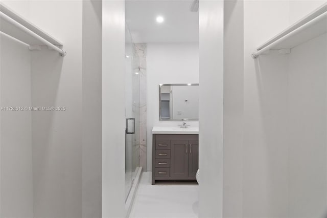 bathroom with a shower with shower door and vanity