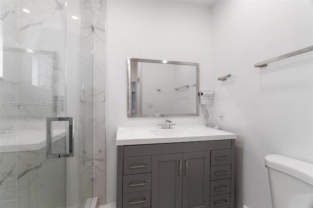 bathroom featuring toilet, a shower with shower door, and vanity