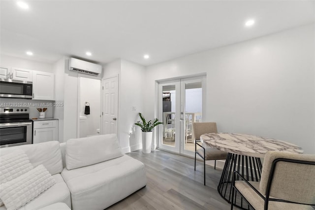 living room with light wood-type flooring, french doors, and a wall mounted air conditioner