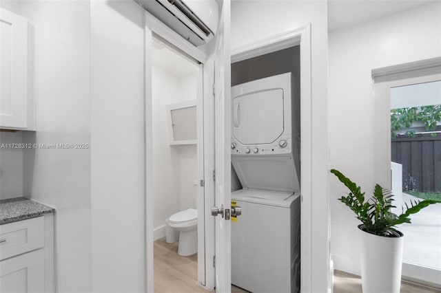 bathroom with toilet, vanity, a wall unit AC, wood-type flooring, and stacked washer / dryer