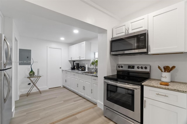 kitchen with decorative backsplash, light hardwood / wood-style flooring, light stone countertops, appliances with stainless steel finishes, and white cabinets