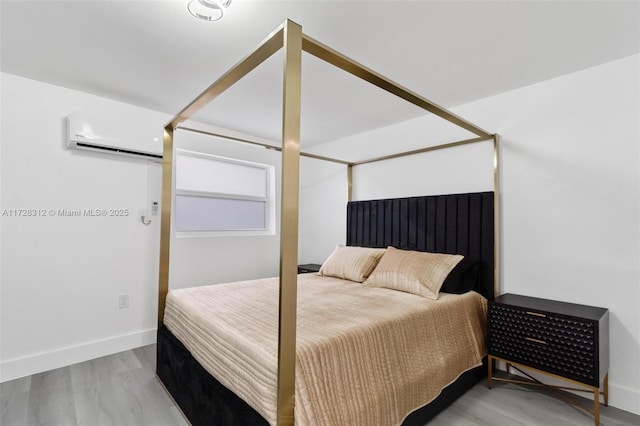 bedroom featuring a wall mounted AC and light hardwood / wood-style flooring