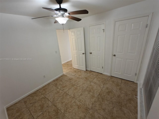 unfurnished bedroom featuring ceiling fan and multiple closets