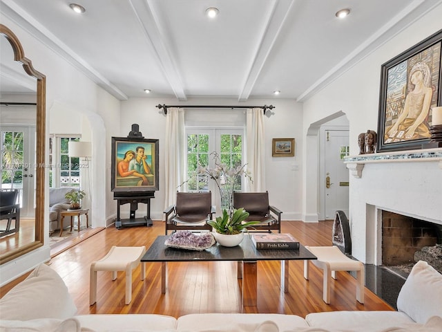 living room featuring french doors, beamed ceiling, crown molding, and light hardwood / wood-style floors