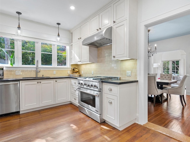 kitchen with stainless steel appliances, white cabinetry, decorative light fixtures, and sink