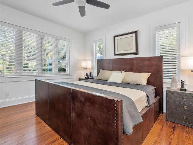 bedroom with ceiling fan, multiple windows, and light wood-type flooring