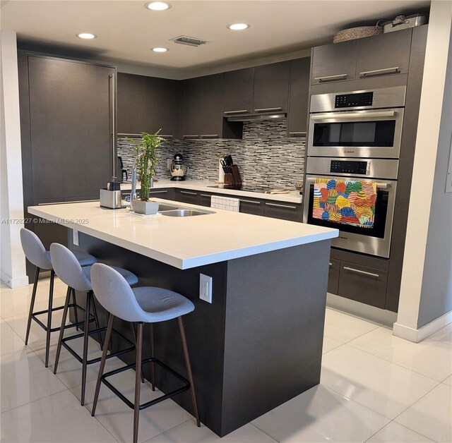 kitchen with light tile patterned flooring, double oven, tasteful backsplash, sink, and black electric stovetop