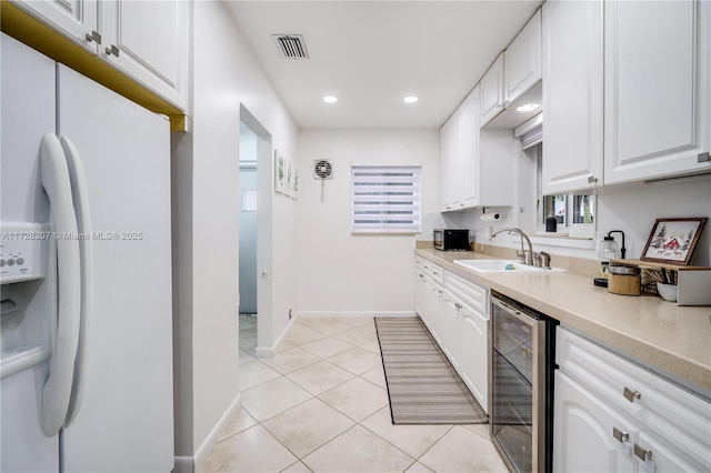 kitchen with light tile patterned floors, white cabinetry, beverage cooler, white refrigerator with ice dispenser, and sink