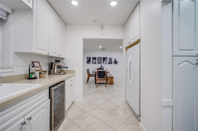 kitchen with white cabinets, white fridge with ice dispenser, light tile patterned floors, and beverage cooler