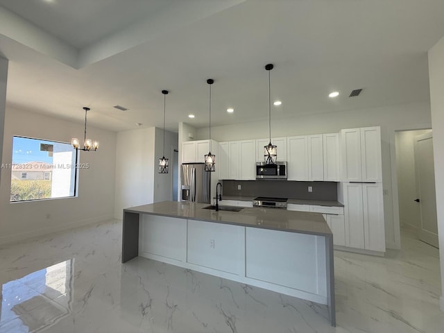 kitchen with sink, a center island with sink, appliances with stainless steel finishes, pendant lighting, and white cabinets