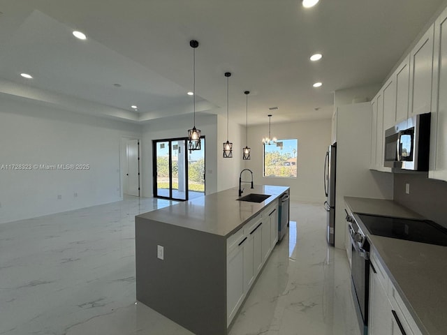 kitchen featuring pendant lighting, sink, appliances with stainless steel finishes, a kitchen island with sink, and white cabinetry