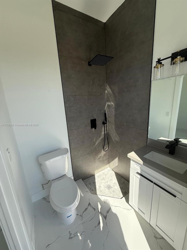 bathroom featuring a tile shower, vanity, and toilet