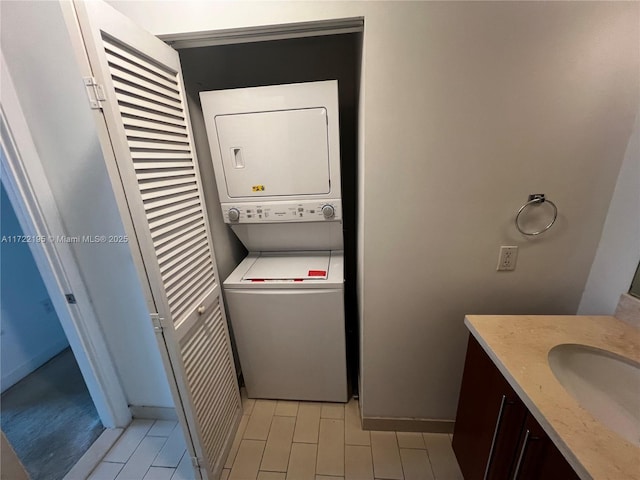 laundry area featuring stacked washer / drying machine and sink