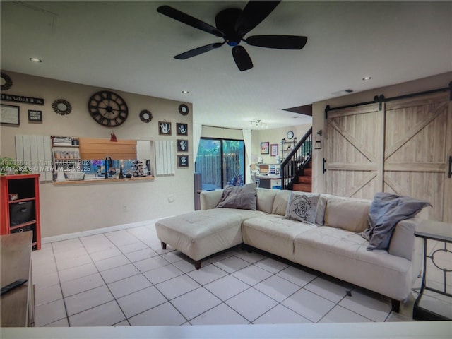 living room with ceiling fan, light tile patterned floors, and a barn door