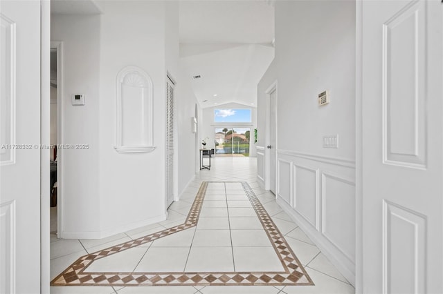 hallway featuring light tile patterned floors and lofted ceiling