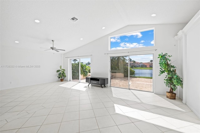 unfurnished living room with ceiling fan, light tile patterned floors, high vaulted ceiling, and a water view