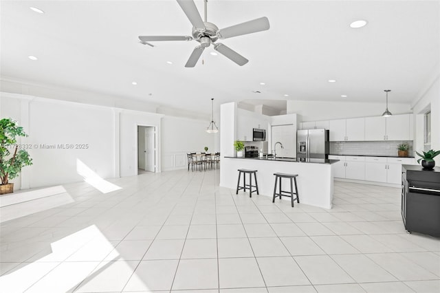 kitchen featuring white cabinetry, appliances with stainless steel finishes, decorative backsplash, lofted ceiling, and pendant lighting