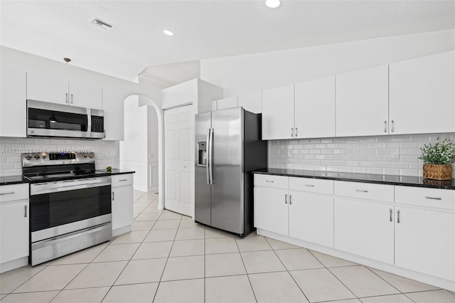 kitchen with white cabinetry, light tile patterned floors, stainless steel appliances, and vaulted ceiling