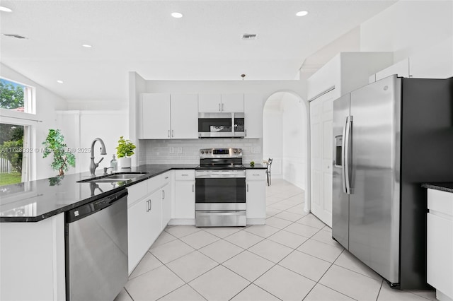 kitchen with kitchen peninsula, decorative backsplash, sink, white cabinetry, and stainless steel appliances