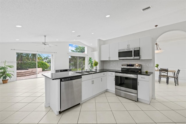 kitchen featuring backsplash, vaulted ceiling, sink, white cabinetry, and stainless steel appliances