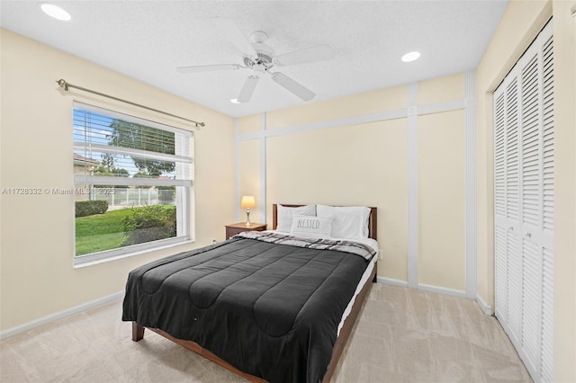 bedroom with ceiling fan, a textured ceiling, a closet, and light carpet