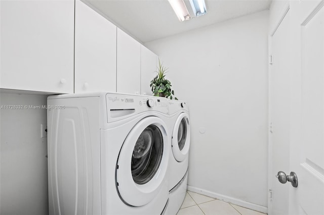 laundry room featuring washer and clothes dryer, light tile patterned floors, and cabinets