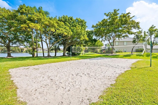 surrounding community featuring a water view, a lawn, and volleyball court