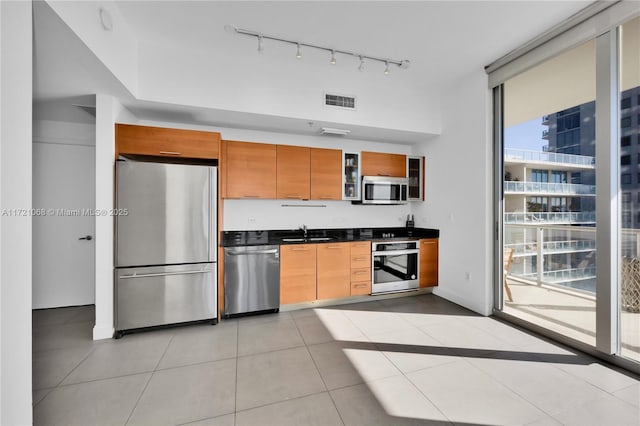 kitchen with light tile patterned floors, stainless steel appliances, a healthy amount of sunlight, and sink