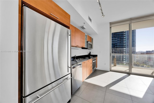 kitchen with light tile patterned flooring, stainless steel appliances, floor to ceiling windows, and sink