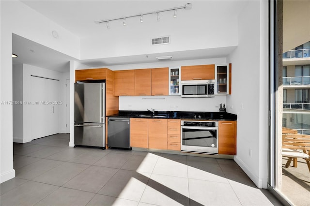 kitchen with appliances with stainless steel finishes, sink, a towering ceiling, and light tile patterned flooring