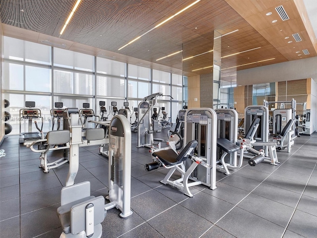 workout area featuring wood ceiling, a high ceiling, and expansive windows