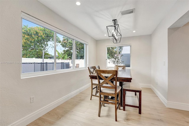 dining area with a healthy amount of sunlight, a chandelier, and light wood-type flooring