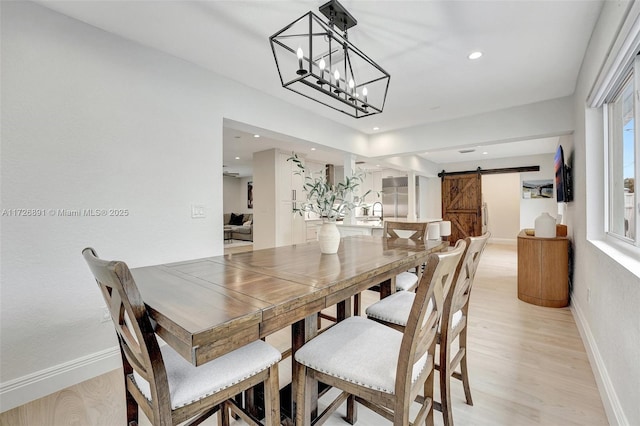 dining area with light hardwood / wood-style floors and a barn door