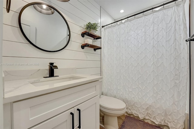 bathroom featuring toilet, vanity, wood walls, and a shower with shower curtain