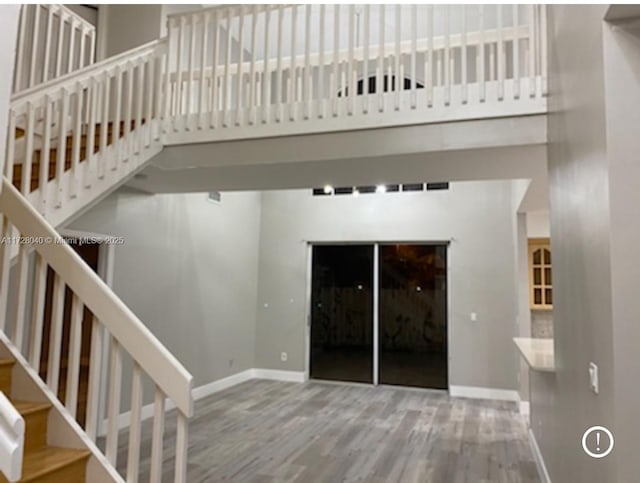 stairway with wood-type flooring and a towering ceiling