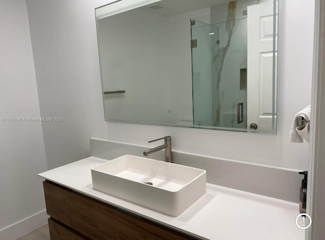 bathroom with a shower with shower door and vanity