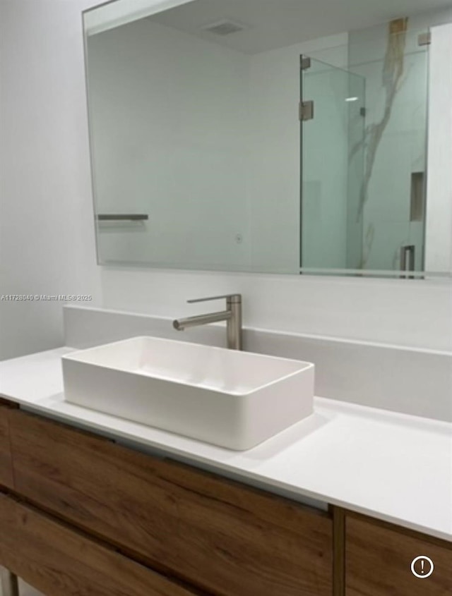 bathroom with a shower with shower door and vanity