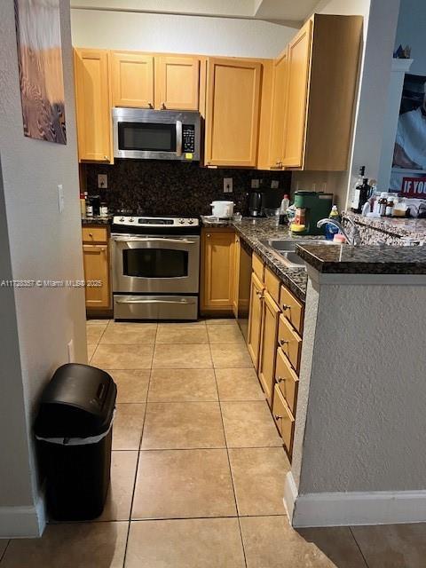 kitchen with tasteful backsplash, light tile patterned floors, appliances with stainless steel finishes, and sink