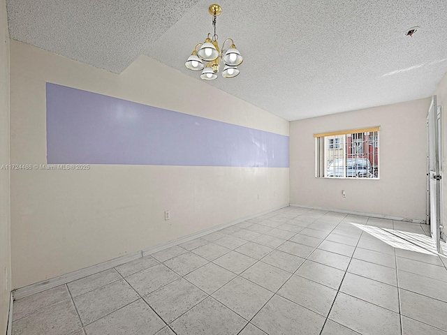 empty room featuring light tile patterned floors, vaulted ceiling, a chandelier, and a textured ceiling