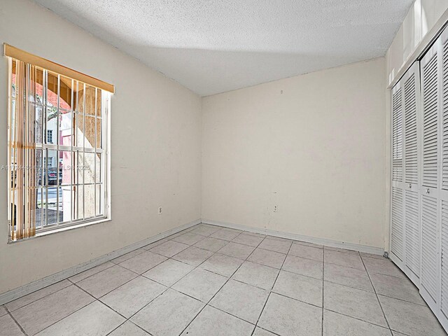 interior space featuring a textured ceiling, a closet, and light tile patterned flooring