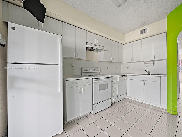 kitchen featuring light tile patterned floors, white appliances, a textured ceiling, and white cabinetry