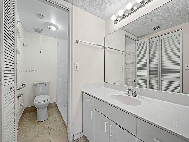 bathroom with toilet, tile patterned flooring, a textured ceiling, and vanity