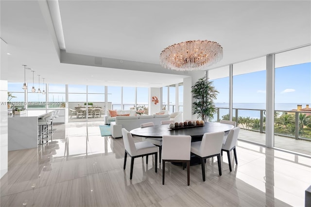 dining room with floor to ceiling windows, a water view, and a chandelier