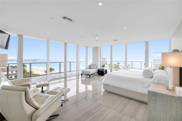 bedroom with multiple windows, expansive windows, and a water view