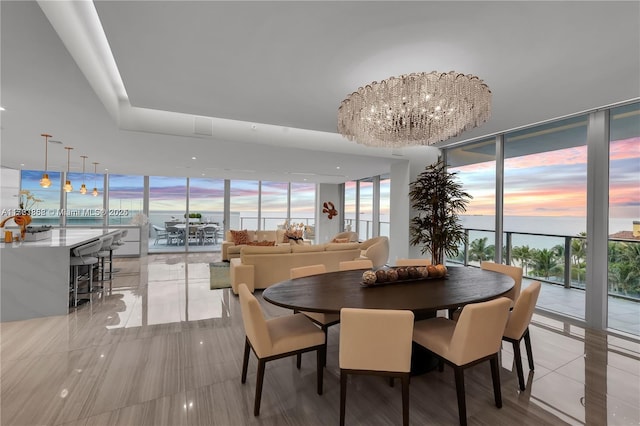 dining room with expansive windows, a water view, and a notable chandelier