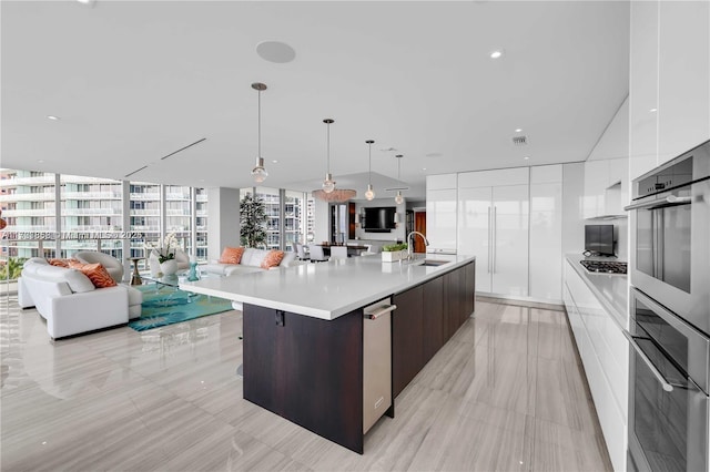 kitchen with appliances with stainless steel finishes, white cabinetry, hanging light fixtures, dark brown cabinets, and a spacious island