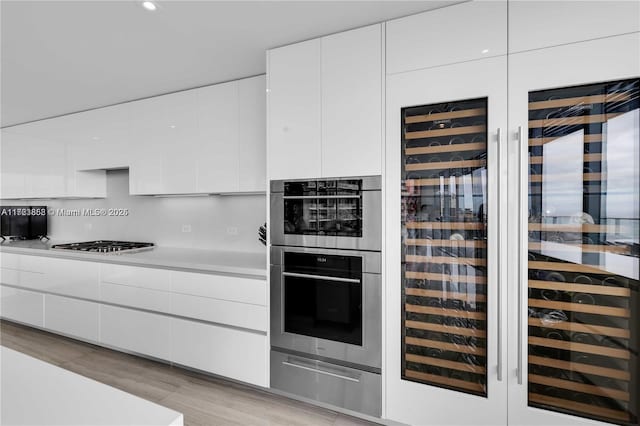 kitchen featuring gas stovetop, white cabinetry, stainless steel double oven, and decorative backsplash