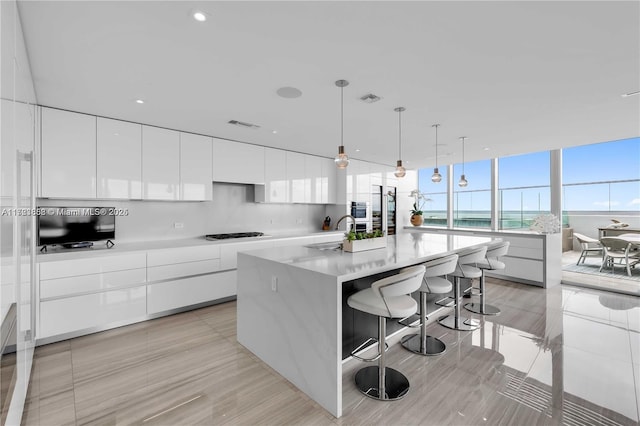 kitchen with a large island, hanging light fixtures, and white cabinets