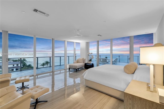 bedroom with expansive windows, a water view, access to exterior, and multiple windows